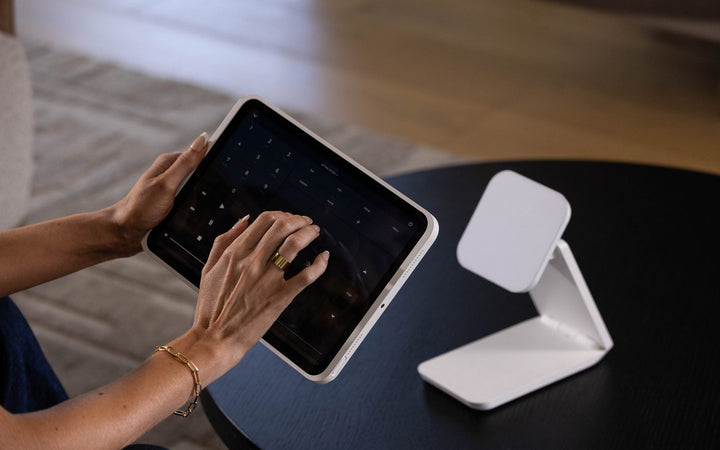 iPad lifted off its white IPORT dock, used in hand at a coffee table for home control