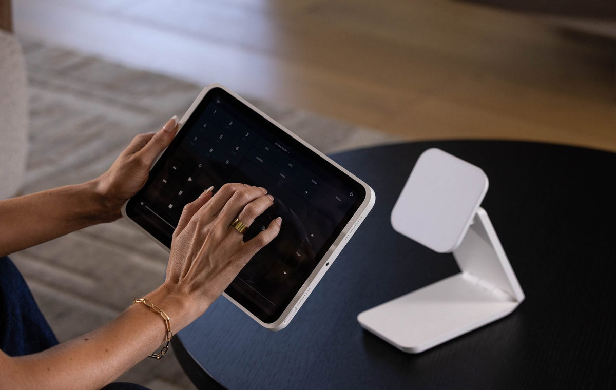 iPad lifted off its white IPORT dock, used in hand at a coffee table for home control