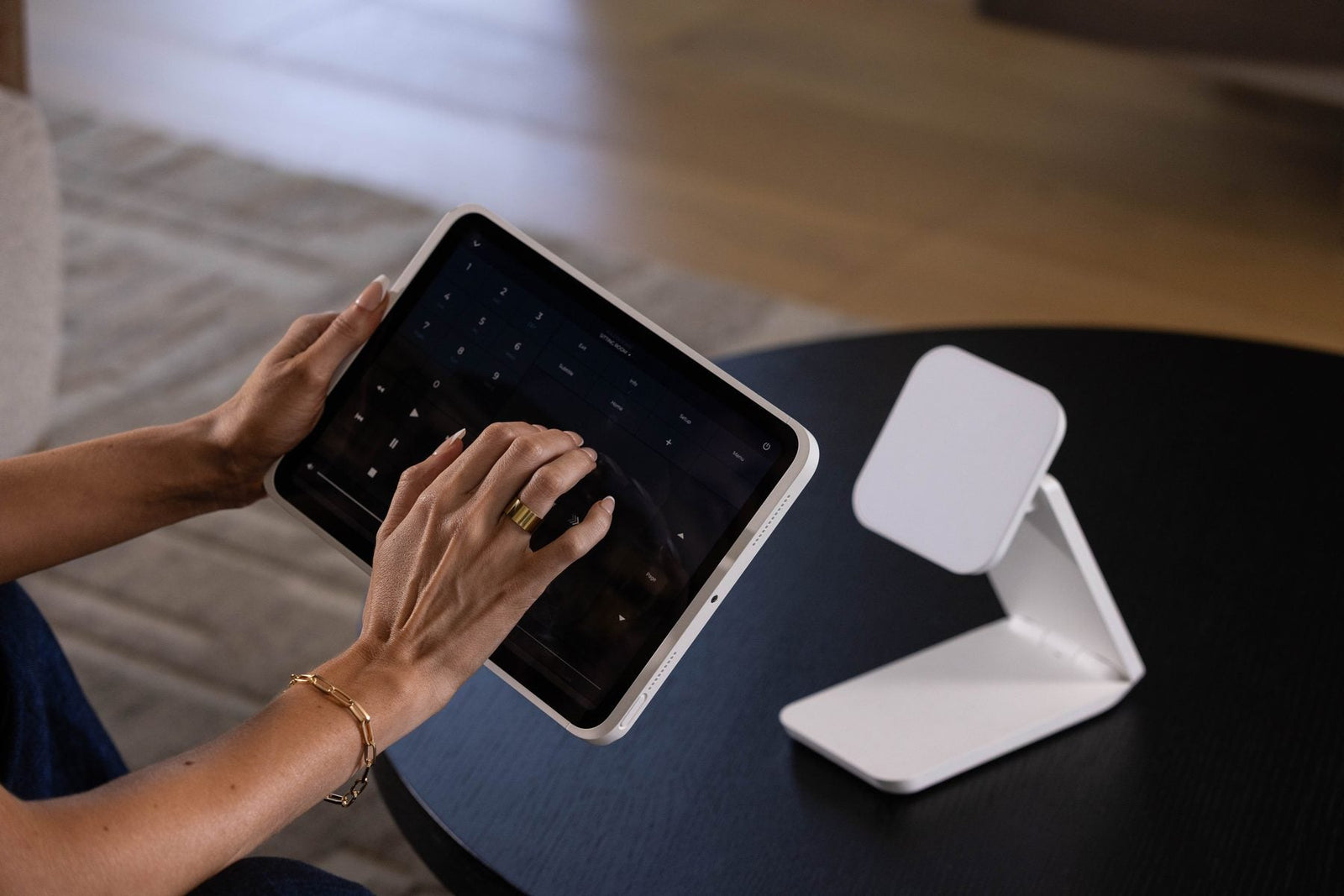 iPad lifted off its white IPORT dock, used in hand at a coffee table for home control