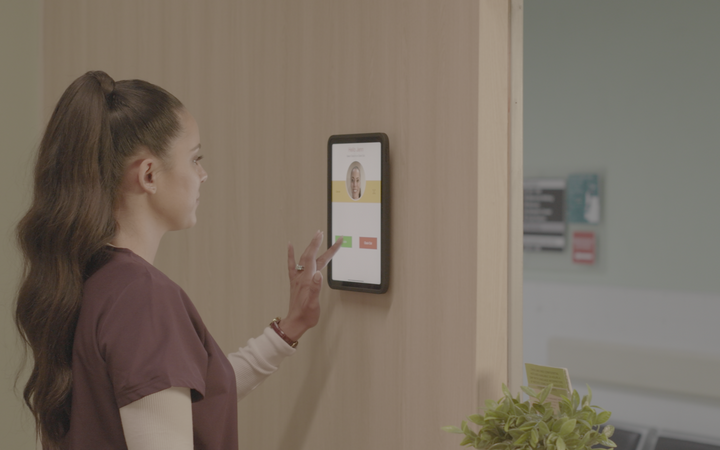 Healthcare worker using iPad biometric time clock with IPORT wall mount