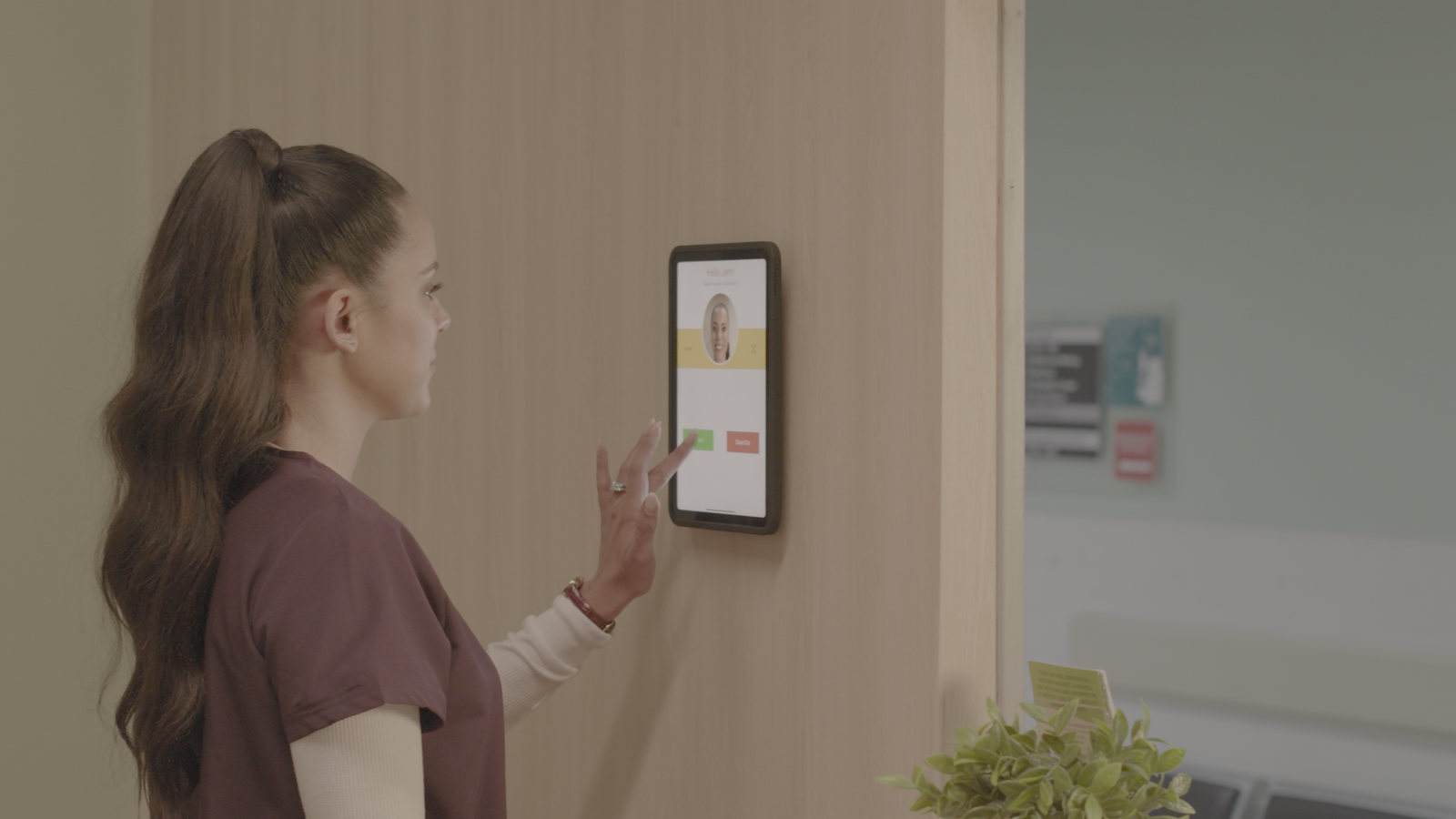 Healthcare worker using iPad biometric time clock with IPORT wall mount