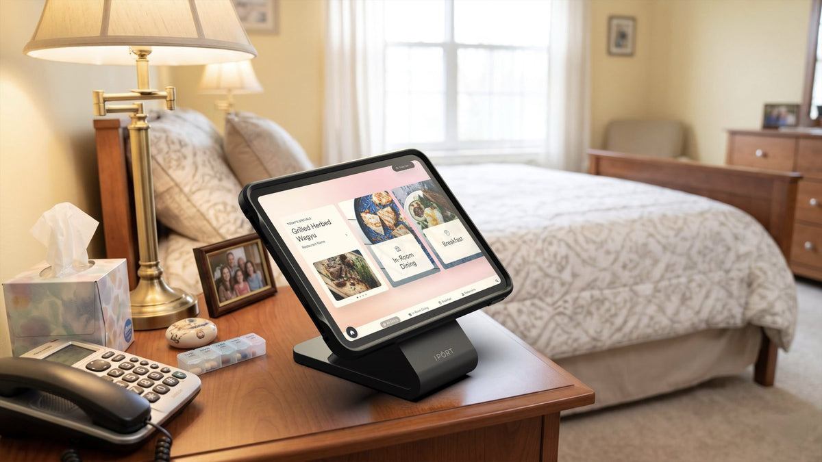 iPad in an IPORT case on a BaseStation at a senior living resident's bedside, showing an in-room dining menu